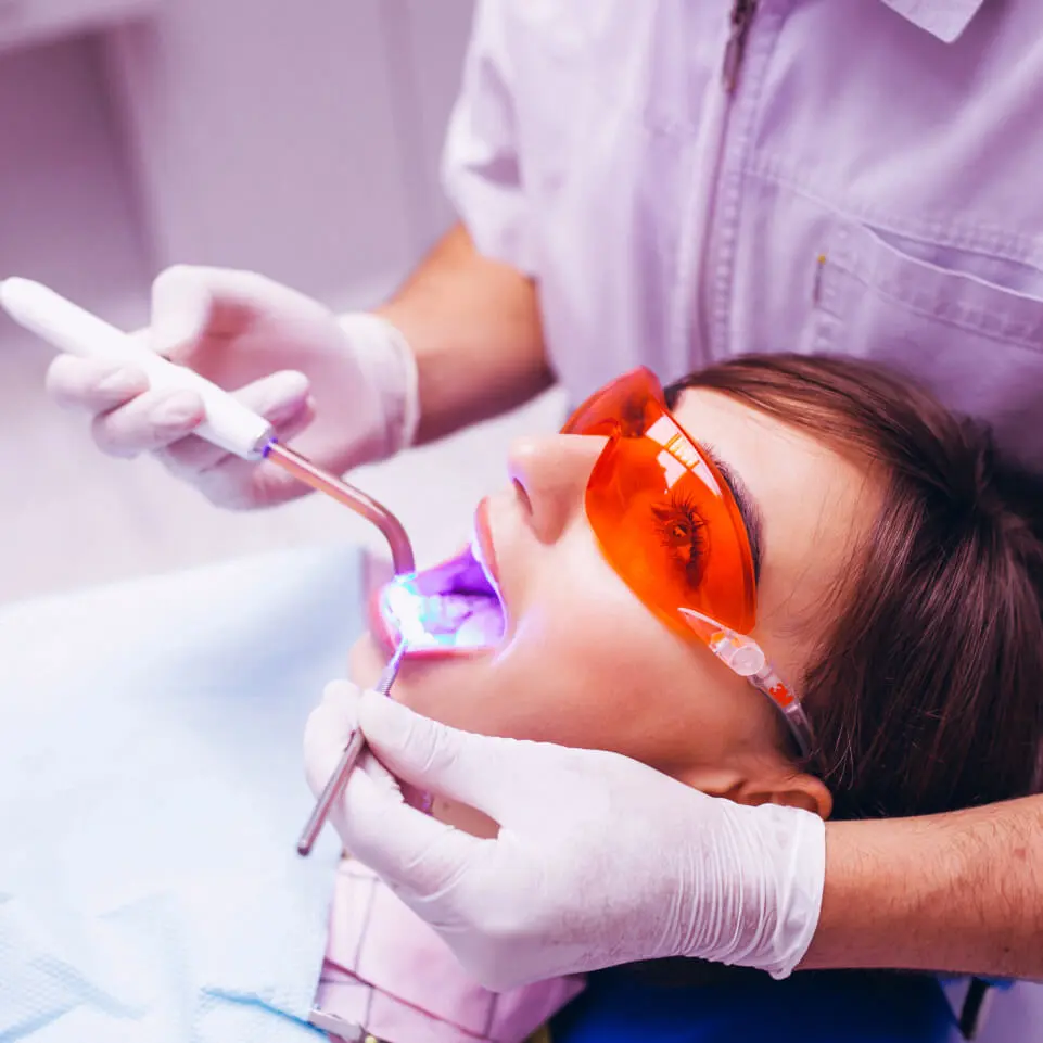 Paciente mulher no dentista recebendo tratamento com laser