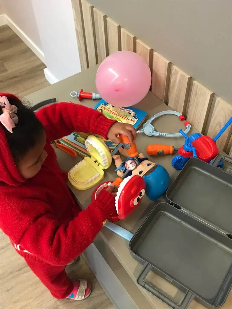 Foto de paciente da Clínica Aurora, sendo uma criança, brincando com proteses de brinquedo.