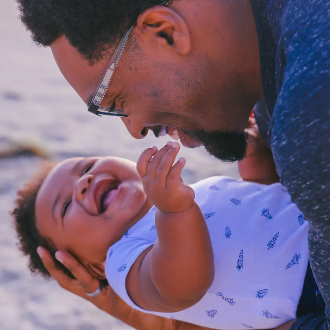 Pai segurando filho bebê, que está sorrindo